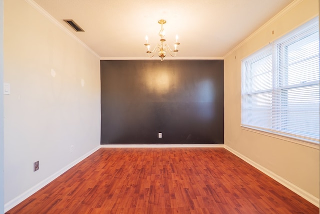 empty room featuring crown molding, a notable chandelier, and hardwood / wood-style flooring