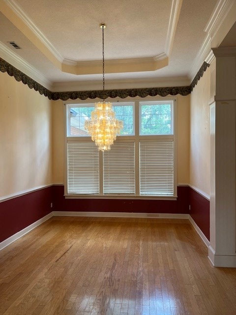 5054 Hammock Trl, Lake Park, GA 31636 - unfurnished dining area featuring a raised ceiling, wood-type flooring, a chandelier, crown molding, and baseboards
