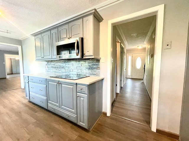 kitchen featuring tasteful backsplash, ornamental molding, and hardwood / wood-style flooring