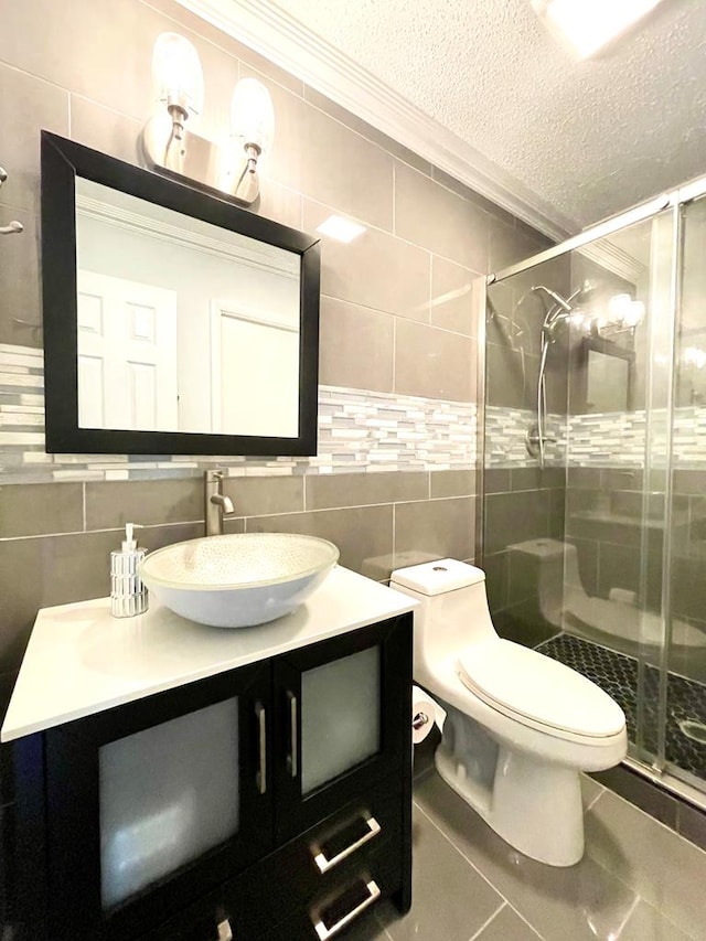 bathroom featuring vanity, a shower with shower door, tile walls, and a textured ceiling