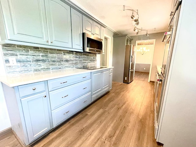 kitchen with backsplash, a notable chandelier, light hardwood / wood-style flooring, and appliances with stainless steel finishes