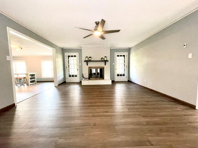 unfurnished living room featuring ceiling fan, ornamental molding, dark hardwood / wood-style flooring, and a brick fireplace