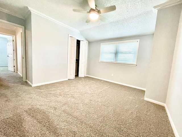 unfurnished bedroom with lofted ceiling, ceiling fan, carpet flooring, a textured ceiling, and a closet