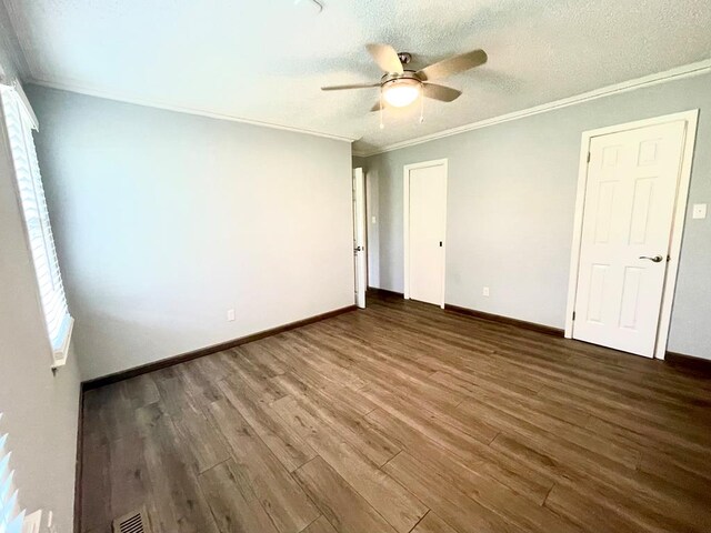 unfurnished bedroom featuring dark hardwood / wood-style flooring, ceiling fan, crown molding, and a textured ceiling