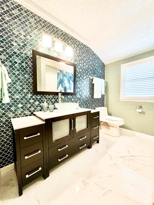 bathroom featuring crown molding, vanity, a textured ceiling, vaulted ceiling, and toilet