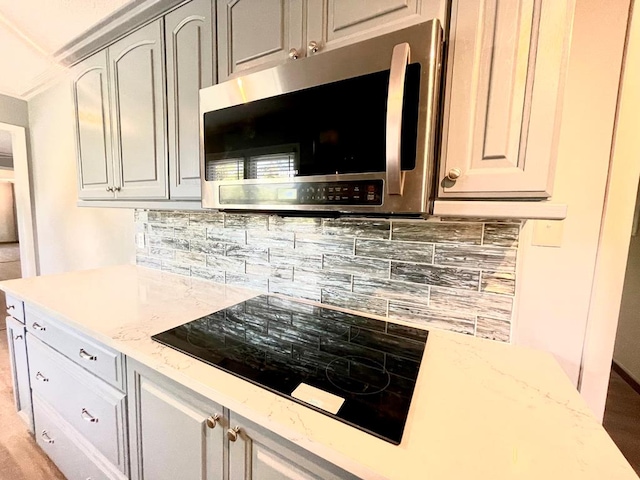 kitchen with black electric cooktop, light stone countertops, and decorative backsplash