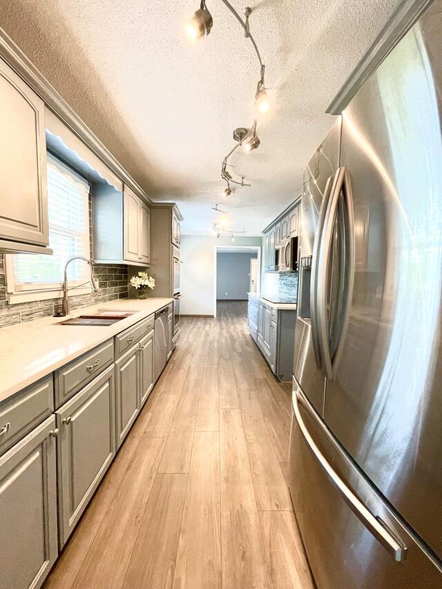 kitchen with stainless steel appliances, sink, gray cabinetry, and light wood-type flooring