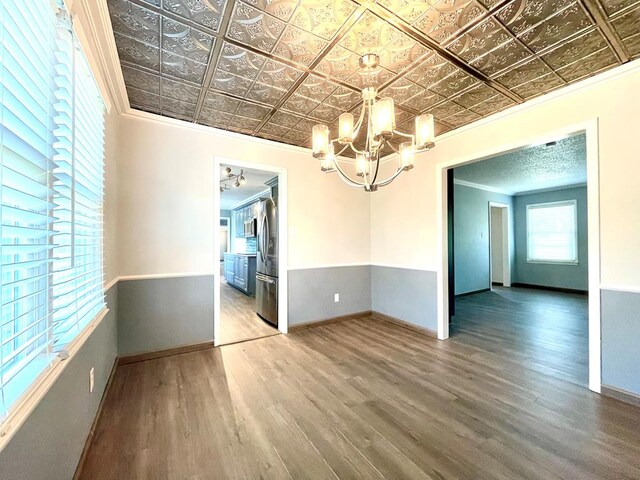 spare room with hardwood / wood-style flooring, ornamental molding, and an inviting chandelier