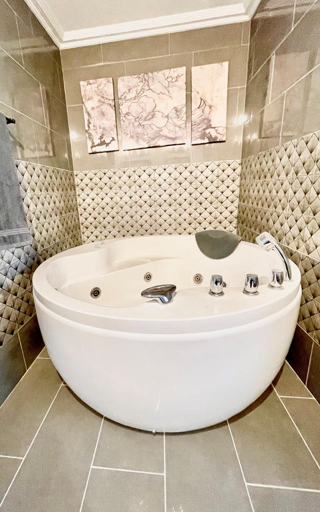 bathroom with tile patterned flooring, a bath, and tile walls