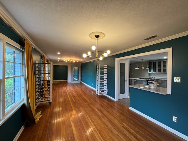 unfurnished dining area featuring a textured ceiling, crown molding, a chandelier, and dark hardwood / wood-style floors