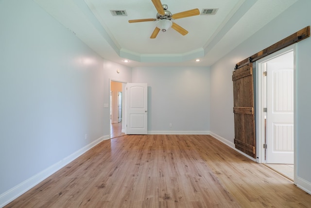 247 Harlee Ln, Ray City, GA 31645 - unfurnished room featuring a tray ceiling, light wood-style floors, a barn door, crown molding, and ceiling fan
