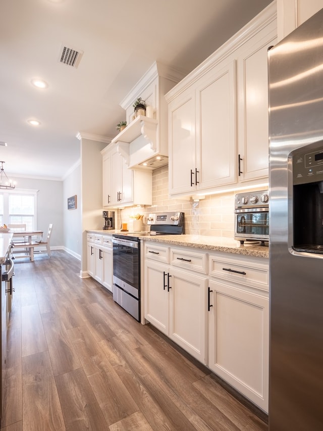 kitchen featuring crown molding, appliances with stainless steel finishes, backsplash, hardwood / wood-style floors, and white cabinets