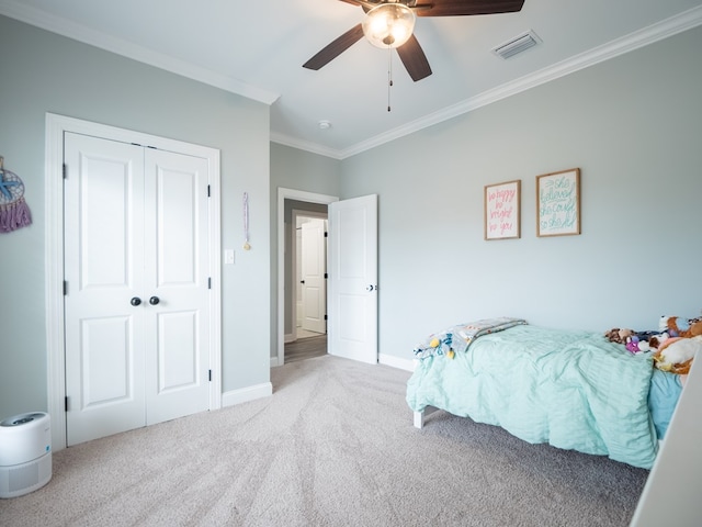 carpeted bedroom featuring ornamental molding, ceiling fan, and a closet