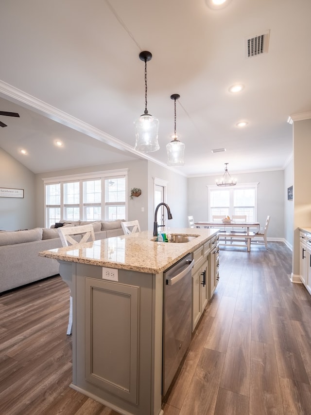 kitchen featuring a breakfast bar, sink, hanging light fixtures, stainless steel dishwasher, and a center island with sink