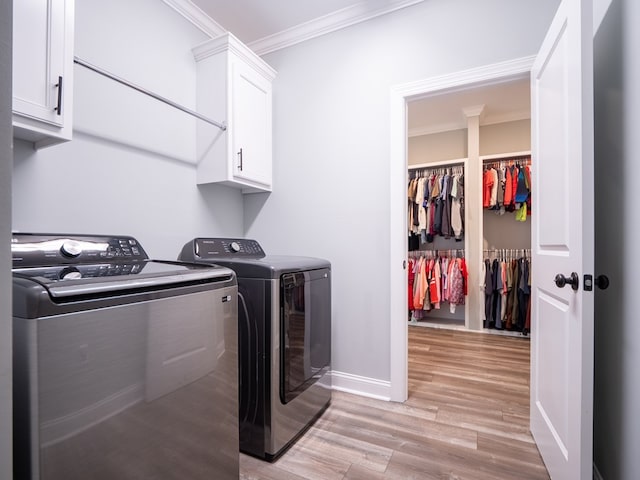 laundry room with cabinets, ornamental molding, washer and dryer, and light wood-type flooring