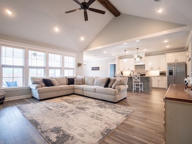 living room featuring hardwood / wood-style flooring, ceiling fan, beam ceiling, and high vaulted ceiling