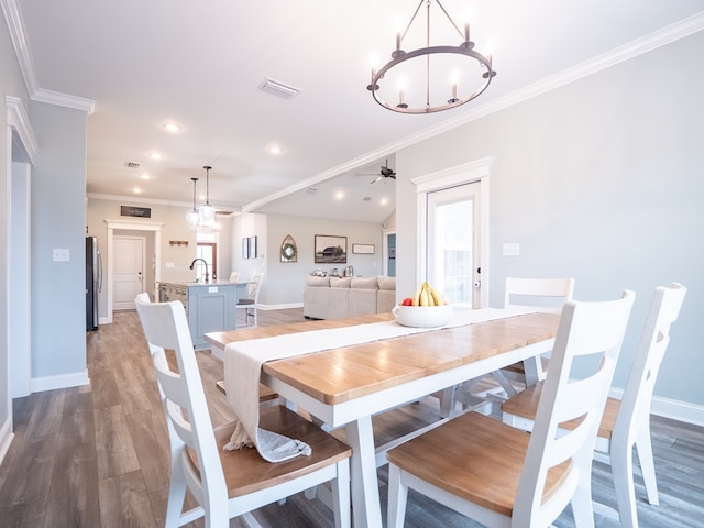 dining room featuring sink, ceiling fan with notable chandelier, wood-type flooring, and ornamental molding