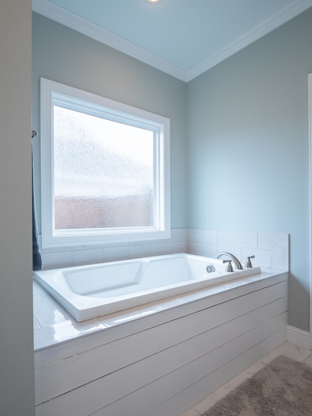 bathroom with tiled tub, crown molding, and plenty of natural light