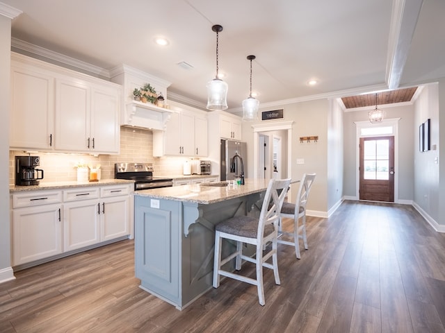 kitchen with pendant lighting, sink, appliances with stainless steel finishes, white cabinetry, and a kitchen island with sink