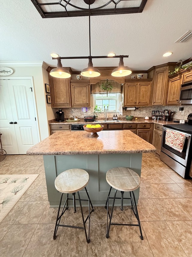 4172 Bright Crk, Hahira, GA 31632 - kitchen featuring stainless steel appliances, a kitchen island, a textured ceiling, tasteful backsplash, and crown molding