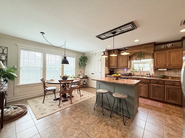 4172 Bright Crk, Hahira, GA 31632 - kitchen with healthy amount of natural light, a center island, backsplash, brown cabinets, and a textured ceiling