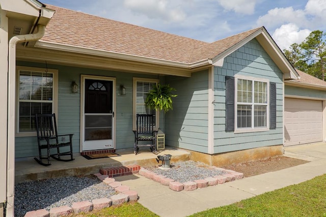 view of exterior entry with an attached garage, covered porch, driveway, and a shingled roof