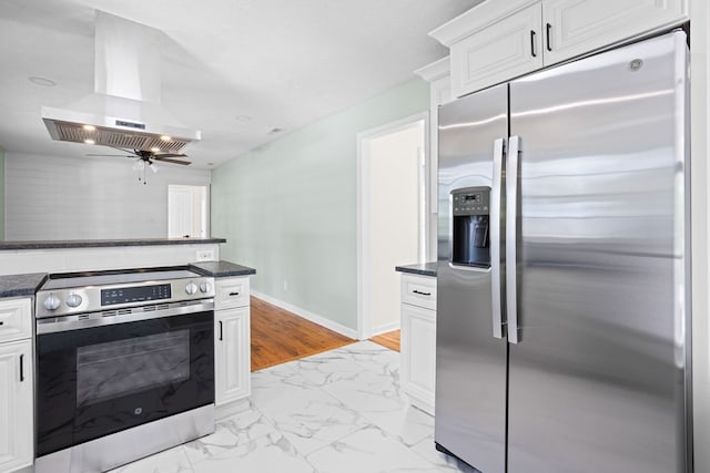 kitchen featuring island range hood, appliances with stainless steel finishes, baseboards, marble finish floor, and white cabinetry