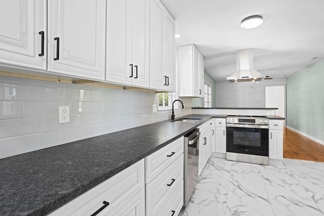 kitchen with white cabinets, appliances with stainless steel finishes, a sink, a peninsula, and island exhaust hood