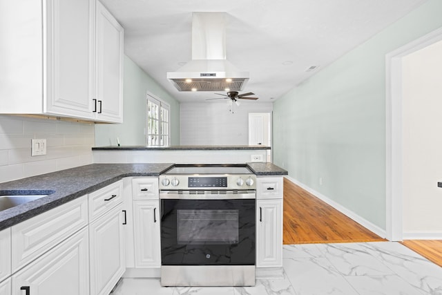 kitchen with a peninsula, white cabinets, island exhaust hood, a ceiling fan, and stainless steel electric range oven