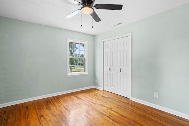 unfurnished bedroom with baseboards, visible vents, wood finished floors, and a closet