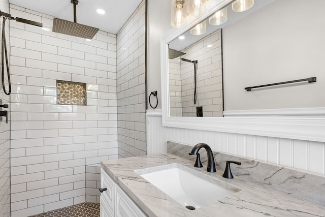 bathroom featuring vanity, wainscoting, and tiled shower