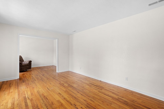 empty room with baseboards, visible vents, and light wood-type flooring