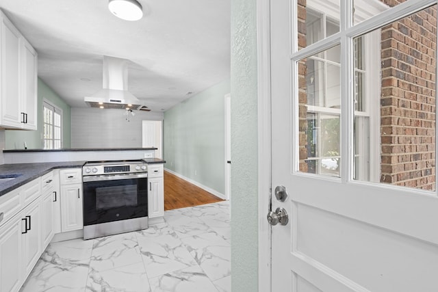 kitchen with stainless steel electric range oven, dark countertops, ventilation hood, marble finish floor, and white cabinetry