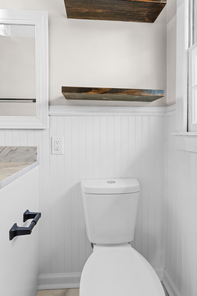 bathroom featuring toilet and a wainscoted wall