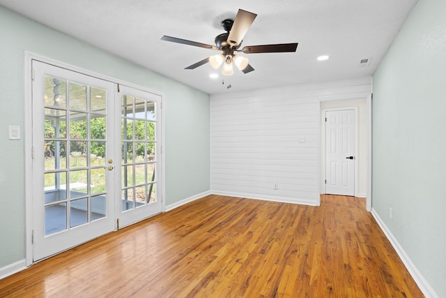 empty room with wood finished floors, baseboards, ceiling fan, recessed lighting, and french doors