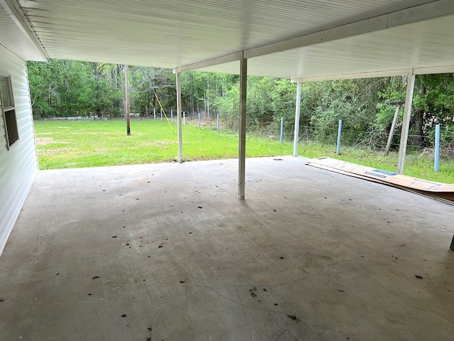 view of patio featuring a wooded view, a carport, and fence