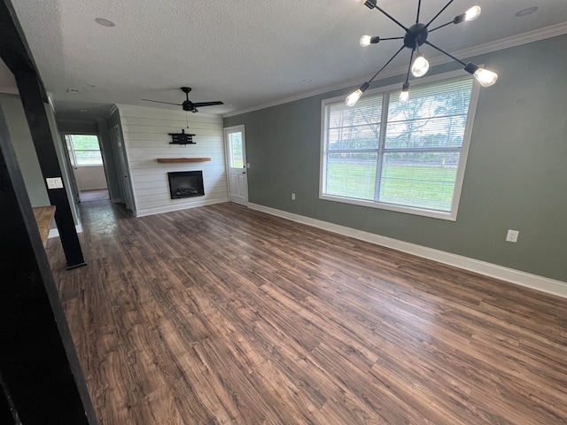 unfurnished living room featuring a fireplace, a textured ceiling, ornamental molding, and dark wood finished floors