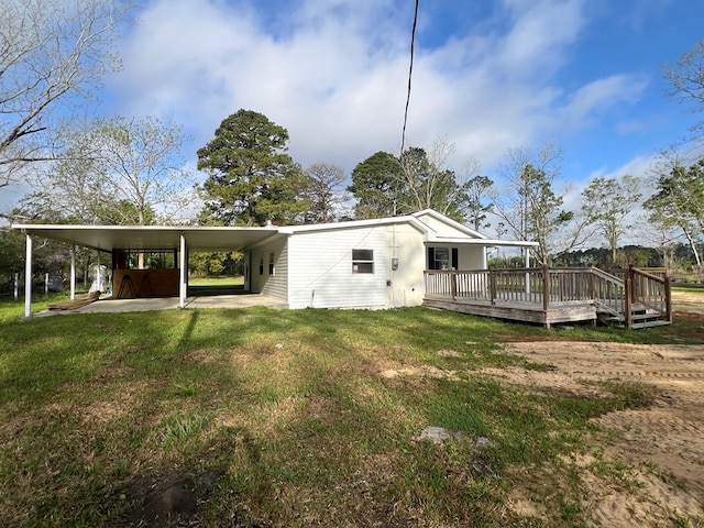 rear view of property featuring an attached carport, a yard, and a wooden deck