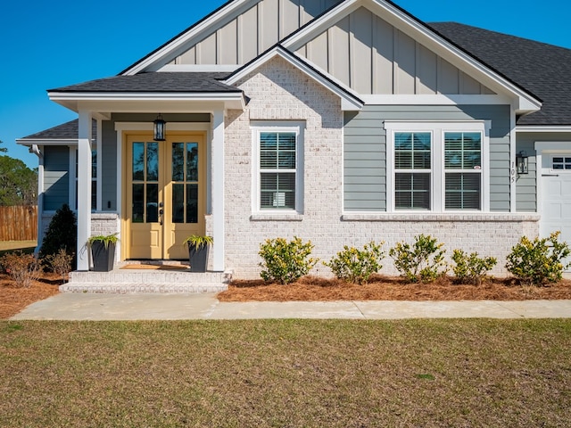 view of front facade with french doors, brick siding, board and batten siding, and roof with shingles