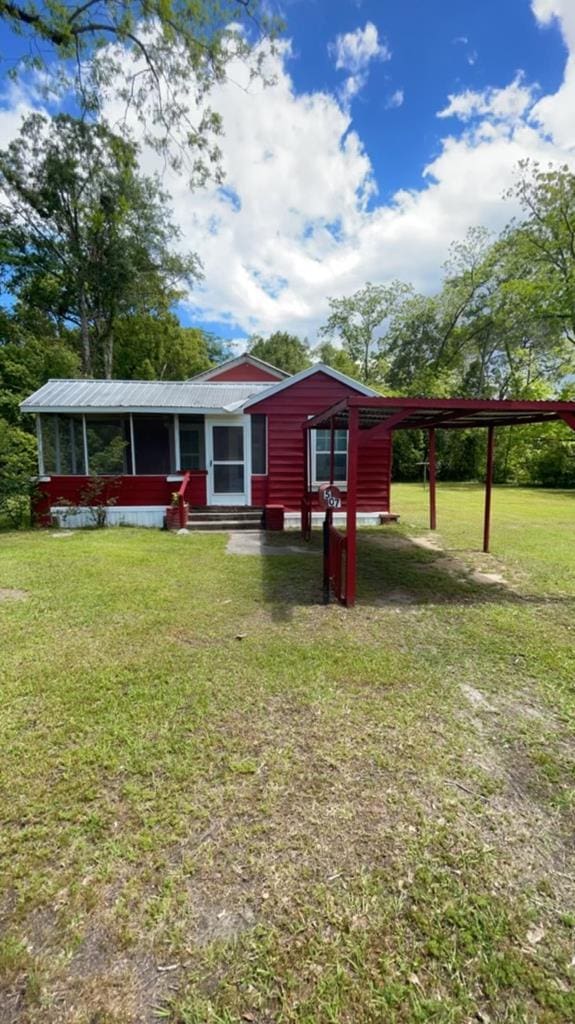 view of front of property featuring entry steps, a carport, a front lawn, and metal roof