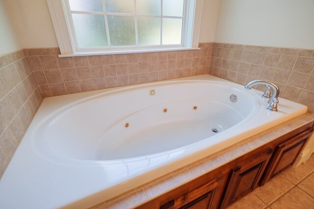 bathroom with a tub to relax in, tile patterned floors, and tile walls