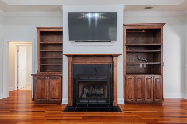 unfurnished living room with a tiled fireplace, dark hardwood / wood-style floors, and ornamental molding