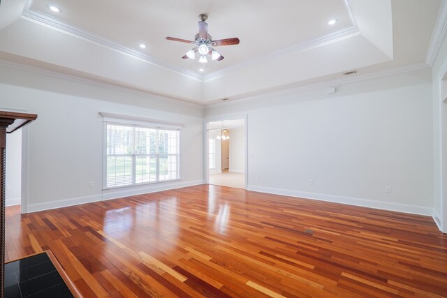 unfurnished living room featuring a raised ceiling, ornamental molding, and light wood-type flooring