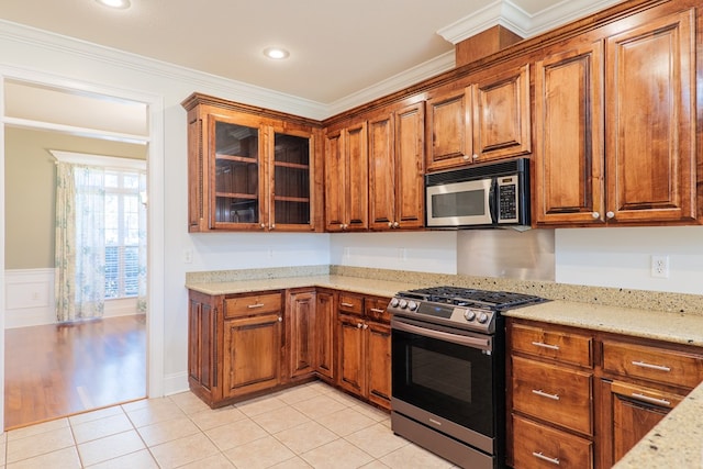 kitchen featuring crown molding, light tile patterned floors, stainless steel appliances, and light stone counters