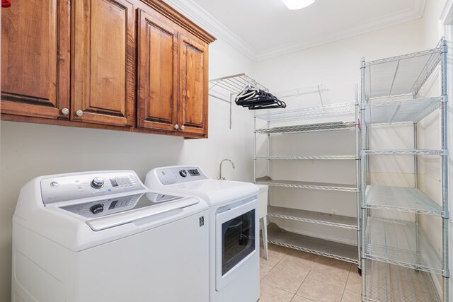 washroom with cabinets, light tile patterned flooring, ornamental molding, and washing machine and clothes dryer