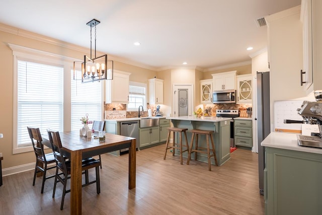 dining space featuring sink, wood-type flooring, crown molding, and an inviting chandelier