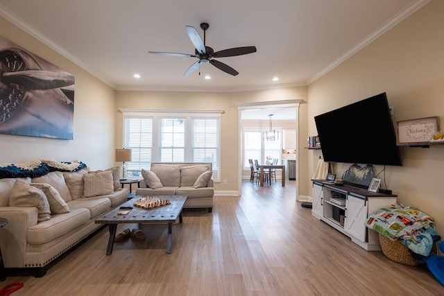 living room featuring light wood-type flooring, crown molding, and ceiling fan with notable chandelier