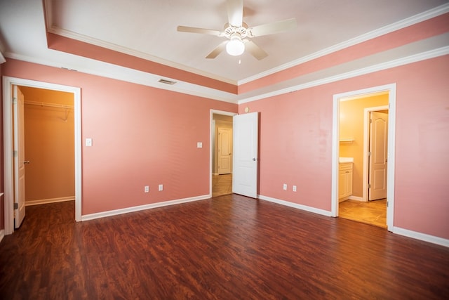 unfurnished bedroom with a spacious closet, ornamental molding, and dark hardwood / wood-style floors