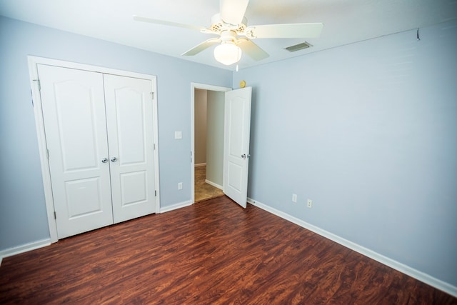 unfurnished bedroom with dark wood-type flooring, a closet, and ceiling fan