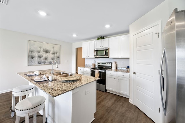 kitchen with a breakfast bar area, dark wood-type flooring, a sink, white cabinetry, and appliances with stainless steel finishes